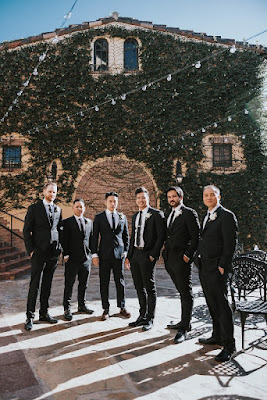 groom and groomsmen posing in suits with hands in pockets