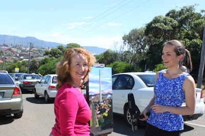 Industrial heritage artist Jane Bennett being interviewed with plein air painting of Port Kembla Copper Copper Stack