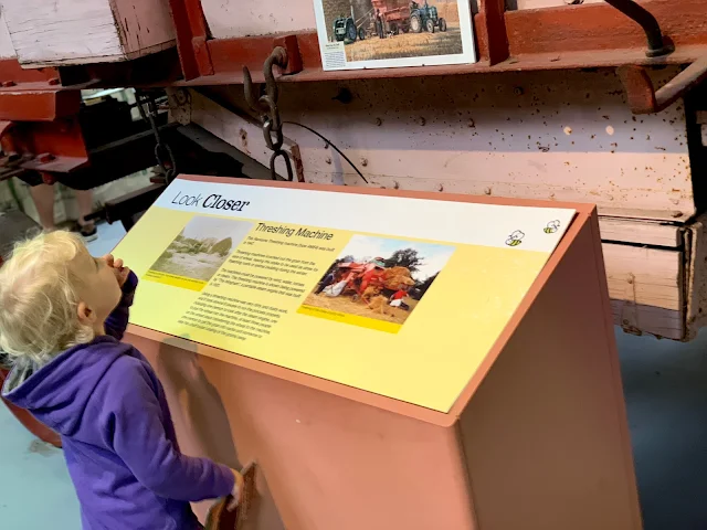 child looking at a thrashing machine in the Discovery Barn at Barleylands Essex