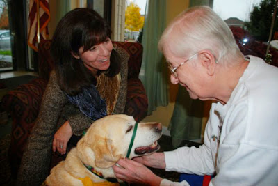 Moon lends a little love to Juanita Murphy at Emeritus Senior Living in Vancouver, Wash., as handler Lisa Locke looks on