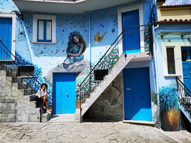 Muro di casa colorato d'azzurro e donna seduta sulle scale