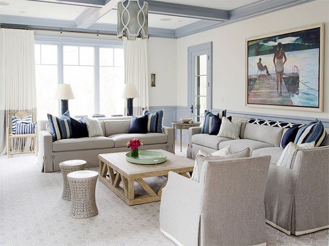 Living room with two neutral sofas with blue accent pillows, matching arm chairs, wood coffee table and two tone curtains