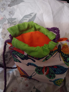 Drawstring bag in butterfly print with coordinating casing fabric. Bag is open to show coordinating linging. Drawstring is braided cotton worsted yarn in additional color.