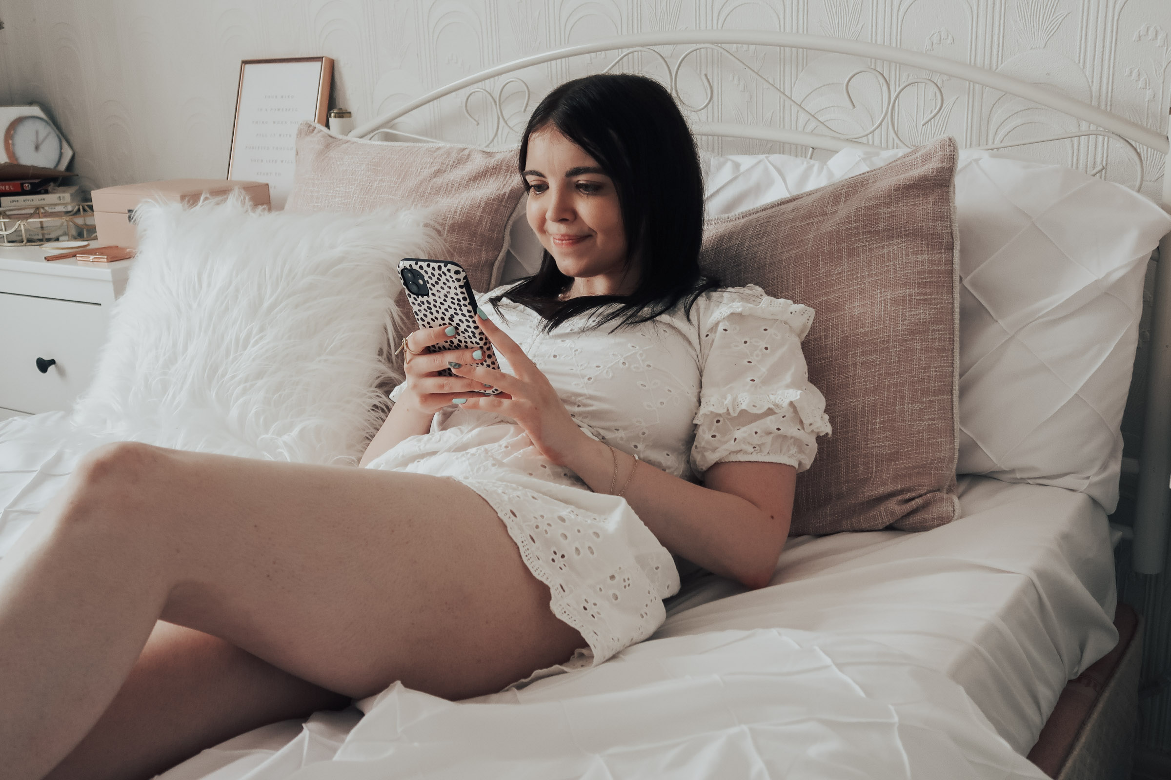 A woman lying on bed holding an Iphone
