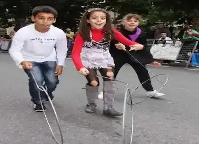 من ألعاب الأطفال القديمة زمان: لعبة العصا والطوق لأطفال يجرون بالشارع