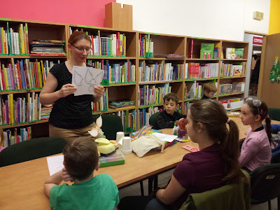 Na zdjęciu bibliotekarz pokazuje uczestnikom zajęć kontury Nudzimisia