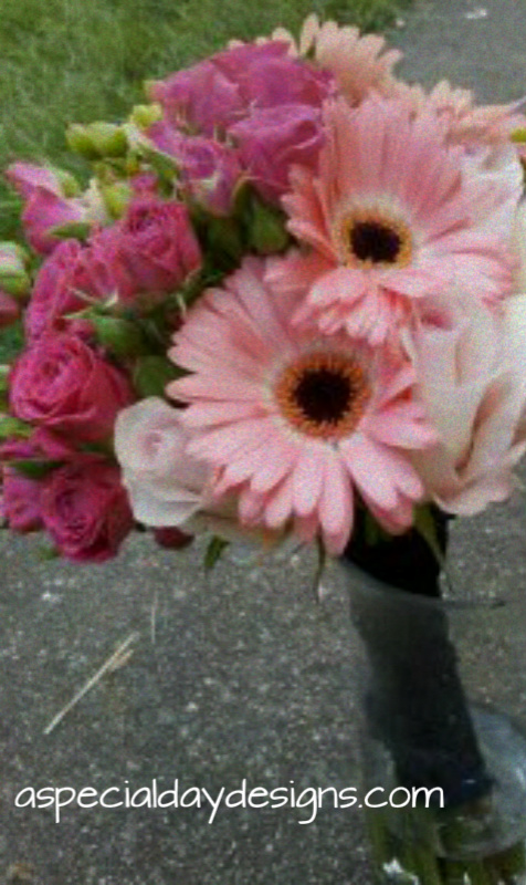 Shades of pink in gerberas roses and spray roses with a navy stem wrap 