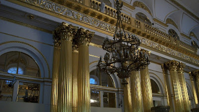 A chandelier in front of golden pillars inside the Hermitage.