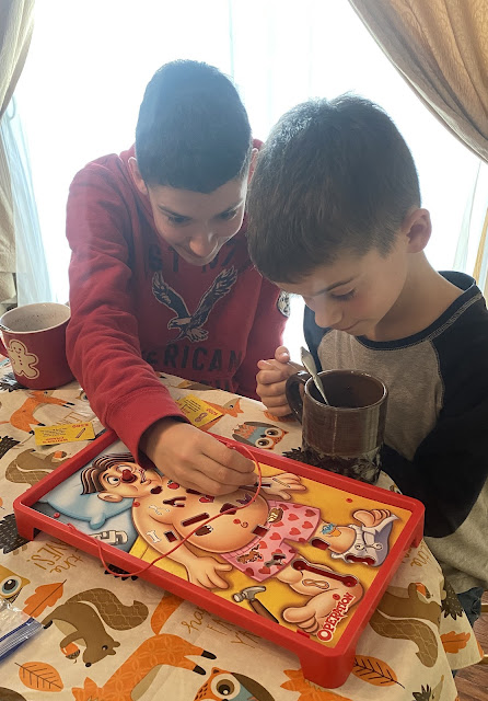 boys playing operation with mugs of hot chocolate