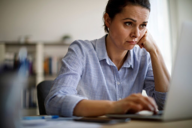 A female worker looking worried in front of a laptop