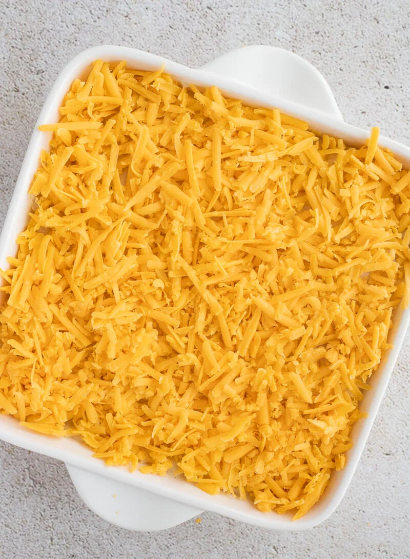 Potato pie with cheese layered on top in the baking dish ready to be baked.