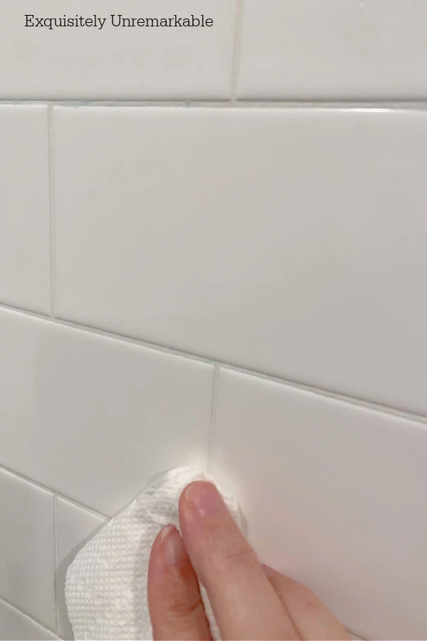 Wiping away excess grout pen paint on tile