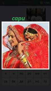 две девушки одеты в сари красного цвета закрывают свои лица