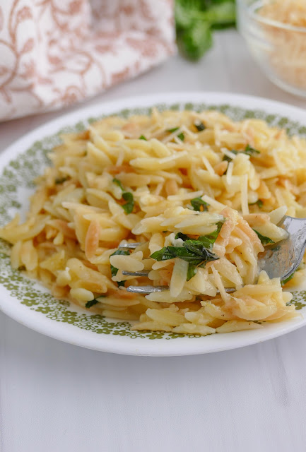 Parmesan Orzo on a white and green plate with a fork.