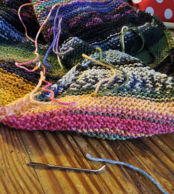 Weaving in the ends on my scrap yarn striped blanket