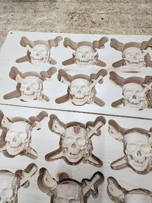 An intricate display of skulls, precisely carved out of a wooden surface using a CNC router, showcasing the detailed craftsmanship and precision of CNC woodworking.