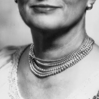 a pearl necklace. the woman is smiling but you can't see the rest of her face above her lips.