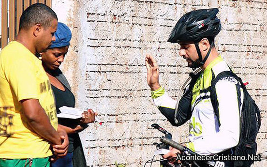 Misionero orando por pareja tras obsequiarles Biblias