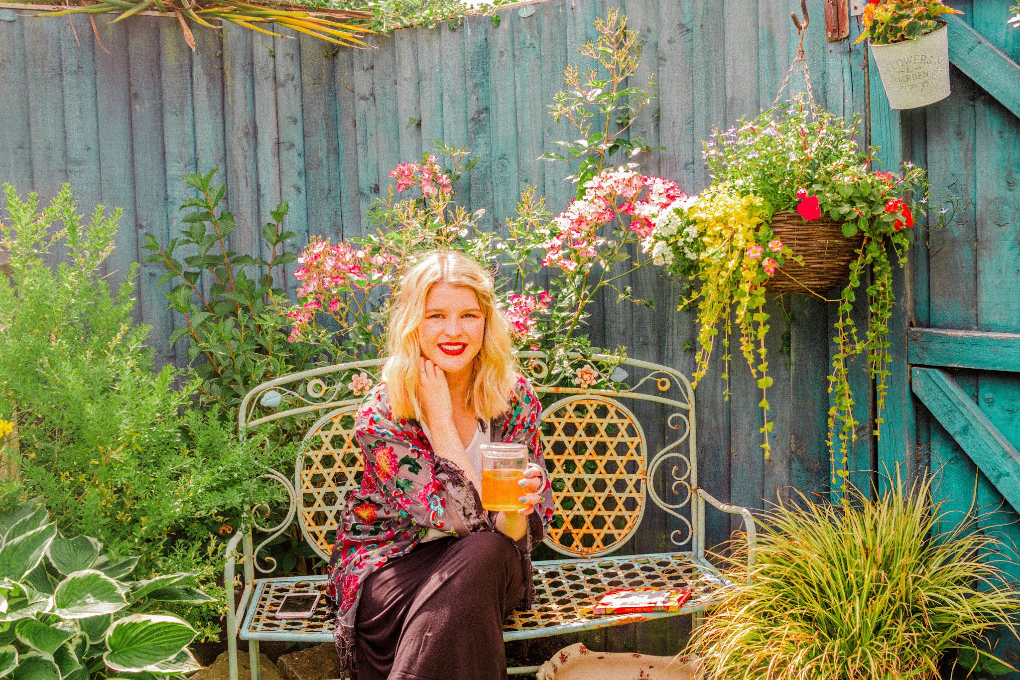 blonde girl in garden reading and drinking tea