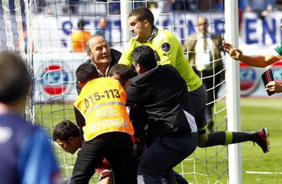 Bursaspor goalkeeper Harun Tekin attempts to kick a fan who invades the field