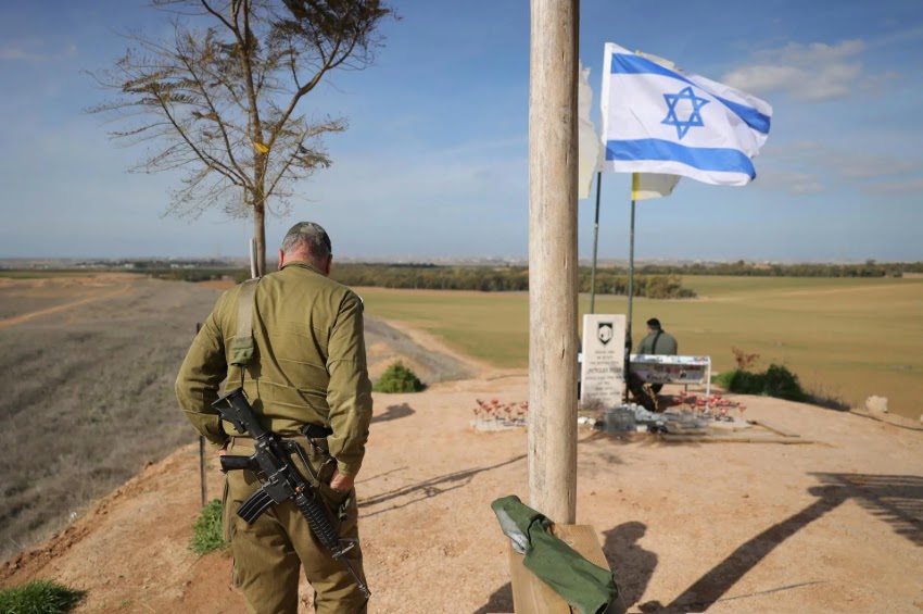 Um soldado israelense armado fica perto de uma bandeira israelense em uma colina perto da fronteira entre Israel e Gaza, no sul de Israel, 19 de janeiro de 2025. (Foto: ABIR SULTAN / EFE / EPA)