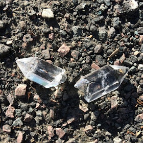 A section of quartz crystal, broken into two pieces, lying on asphalt ground.