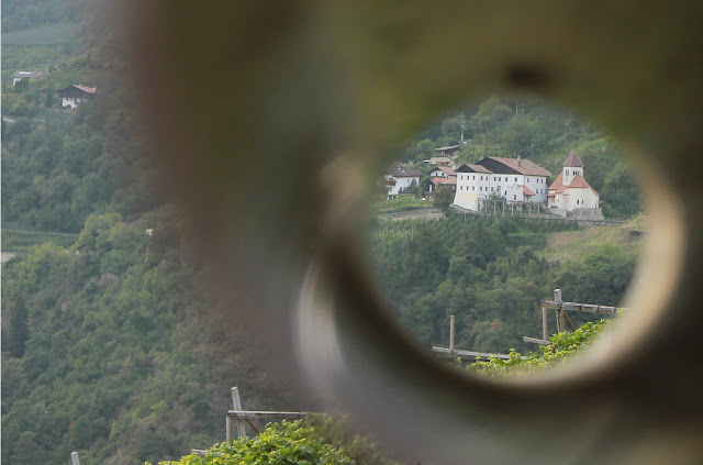 Wioska Tirol ma swoją reprezentacyjną promenadę. Biegnie ona zachodnim skrajem wsi, po zboczach w widokiem na dolinę Adygi. Przy promenadzie ustawiono metalowe rurki, rodzaj lunet, wskazujących opisany na tablicy informacyjnej zabytek. Okrąły "obraz" widziany przez lunetę mieści niewielki kościółek św. Piotra, fragment winnic, fragment sadów jabłoniowych porastających zbocza.