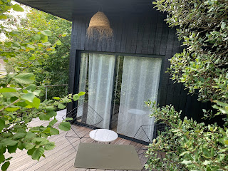 La chambre de l'hôtel s'ouvre sur une terrasse couverte entourée d'arbres et de végétation