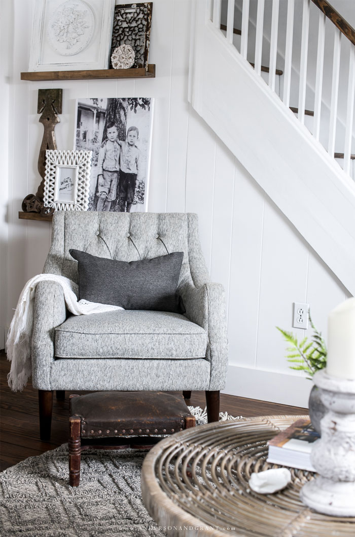 Gray living room chair in front of picture ledge shelves