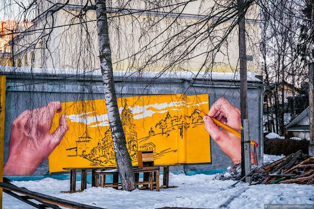 Руки держат картину с изображением Нижегородского кремля