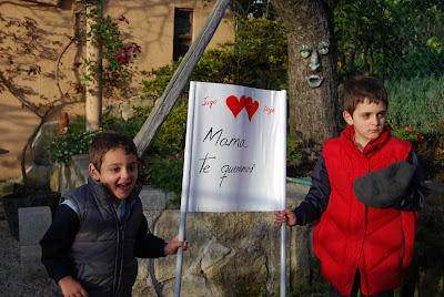 Iago y Diego sujetando una pancarta que dice, mama te queremos