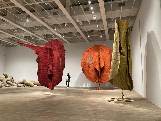 Large sisal sculptures in red, orange and golden yellow hang like creatures from a large gallery's ceiling