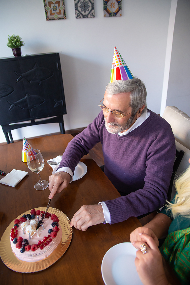 an elderly man cuts birthday cake