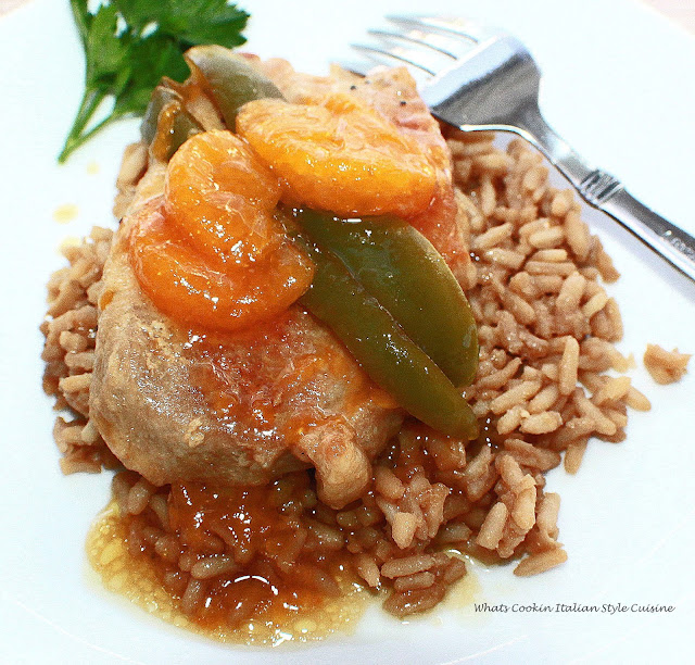 A delicious mandarin orange, peppers Asian sauce with boneless pork pour over rice in a white plate.