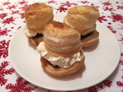 Three puff pastry mince pies filled with whipped cream on a plate.