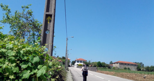 peregrina de Santiago de Compostela na estrada e uma seta amarela no poste