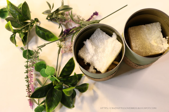 Artificial foliage, flowers and two cans with foam blocks inside