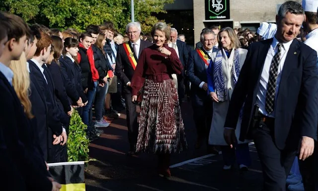 Queen Mathilde wore a burgundy silk top and burgundy printed silk skirt by Natan. Burgundy suede boots and clutch