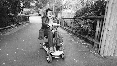 Black and white photo of woman with MS on mobility scooter at Monkey World