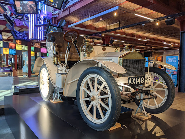 White vintage car with display of screens in background