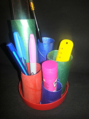 A pencil pot, made from toilet roll tubes and an upturned lid and painted.