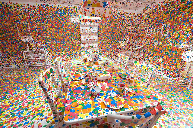an art installation by Yayoi Kusama, a white room and dining table covered in colored dots