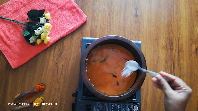 Boiling Thenga Paal Meen Curry over high heat with added salt for seasoning.