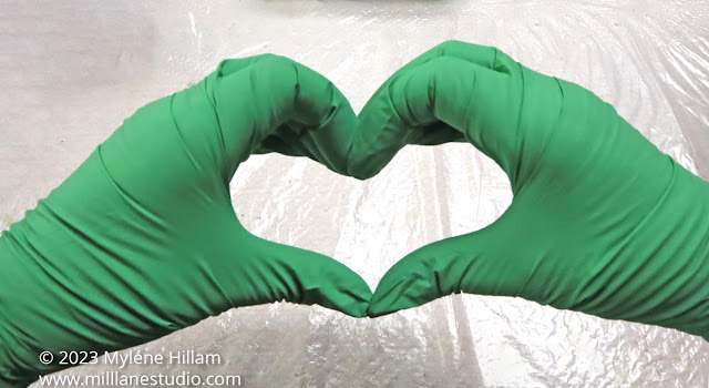 Pair of hands making a heart shape, wearing green gloves