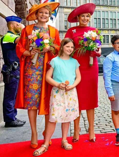 Queen Maxima wore a red midi dress by Natan. Queen Mathilde wore a metallic floral jacquard midi dress by Dries Van Noten