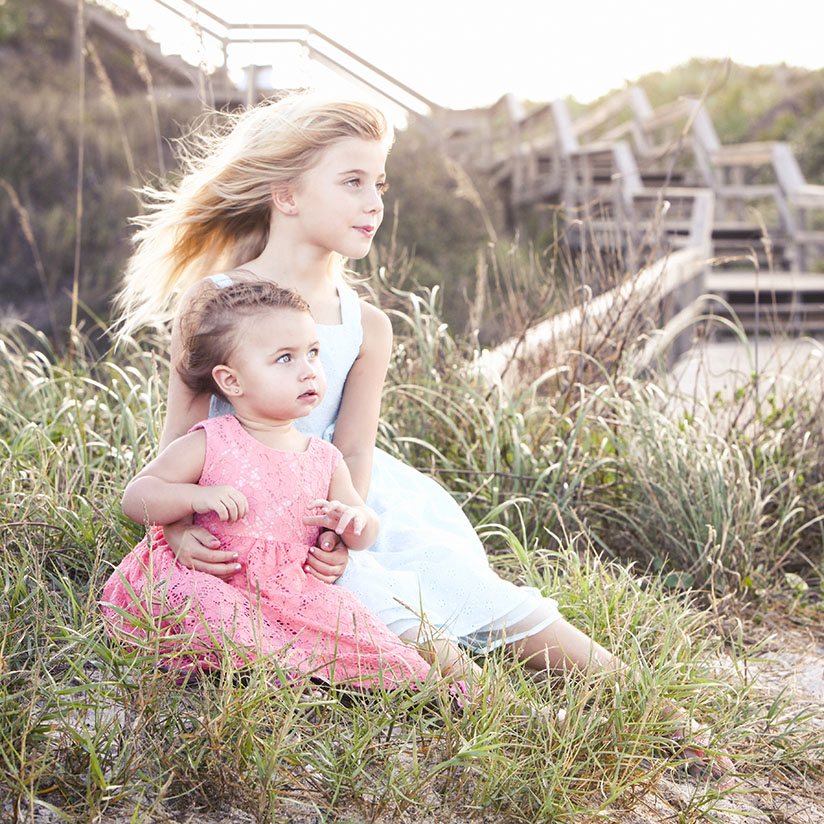 Sisters pose for family photos on the beach