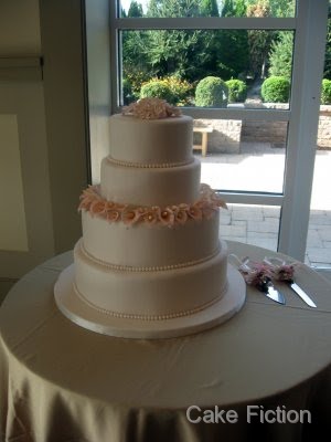 An elegant four tier wedding cake in ivory fondant surrounded by a ring of