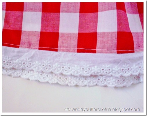 Red and white gingham print pillow case dress for baby.  Close up on the lace.