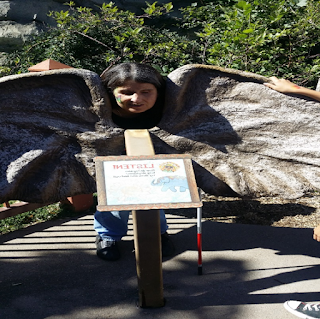 Image of Jo Elizabeth Pinto standing behind a statue that makes her look like she has dinosaur wings