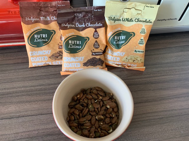 Three packets of chocolate covered pumpkin seeds